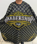 A professional salon cape with a black and yellow paisley pattern being worn by a person standing on a tiled floor.