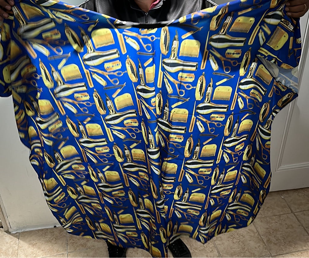 A professional salon cape with a black and yellow paisley pattern being worn by a person standing on a tiled floor.