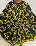 A professional salon cape featuring a luxurious gold crown design on a black background.