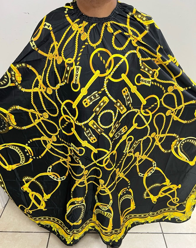 A professional salon cape featuring a luxurious gold crown design on a black background.