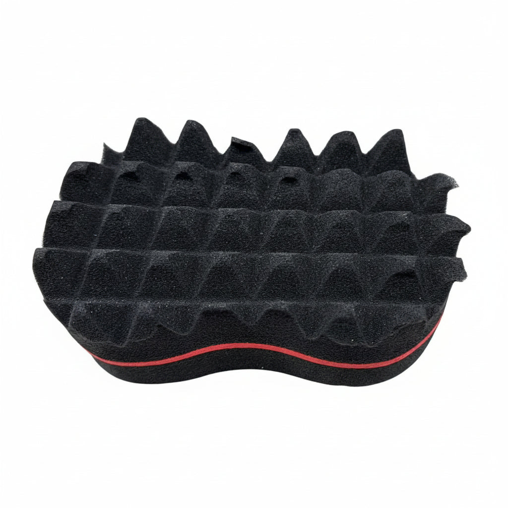 A black barber sponge with red accents on the edges, placed on a textured grey surface.